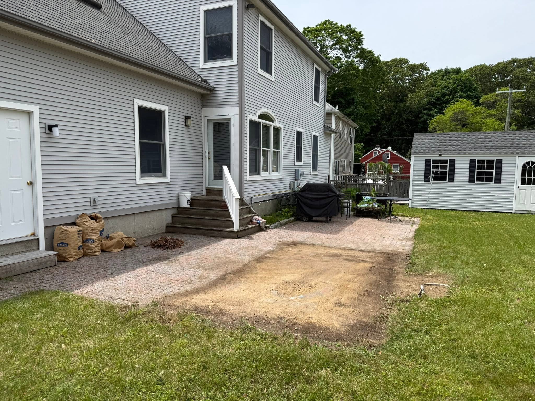 Same patio and lawn after the hot tub was removed, bare ground where it stood